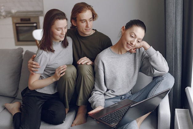 Amigos sentados en una cama en una habitación y usan una computadora portátil