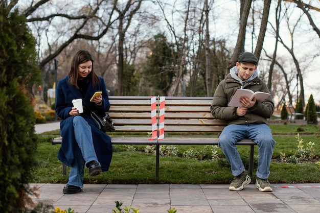 Amigos sentados a distancia y con máscara