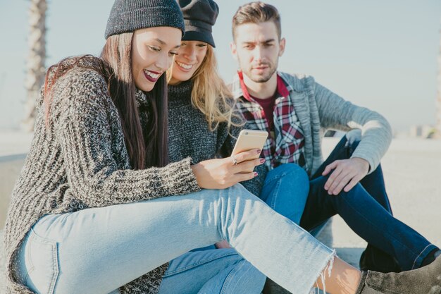 Amigos sentados juntos con smartphone