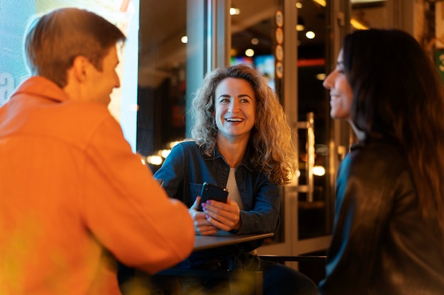 Foto gratuita amigos sentados en una mesa y hablando durante una noche de fiesta