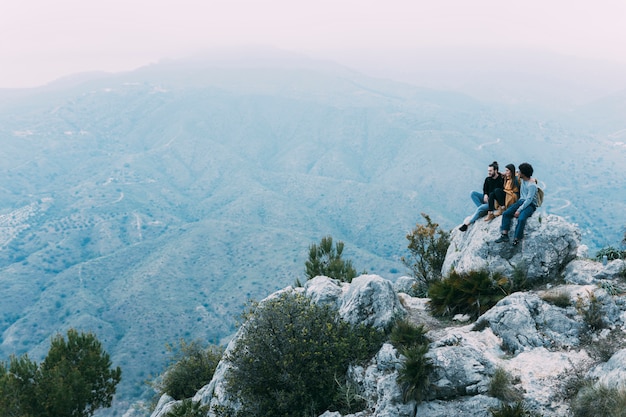 Amigos sentados en roca en la naturaleza