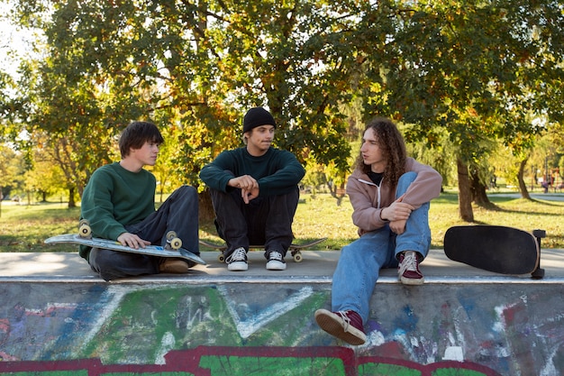 Foto gratuita amigos sentados en skatepark tiro completo