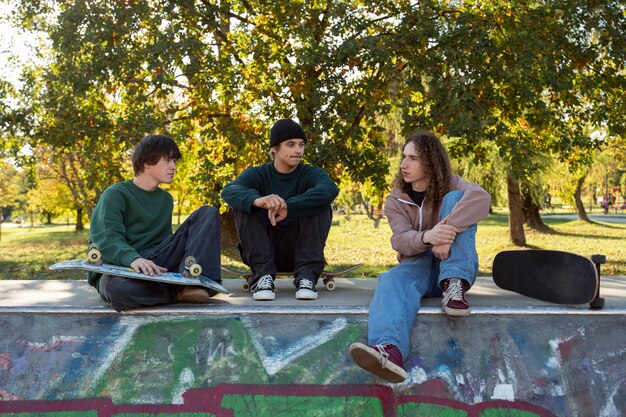 Amigos sentados en skatepark tiro completo