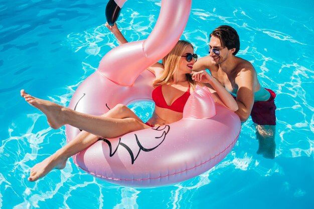 Amigos sonriendo el uno al otro en la piscina