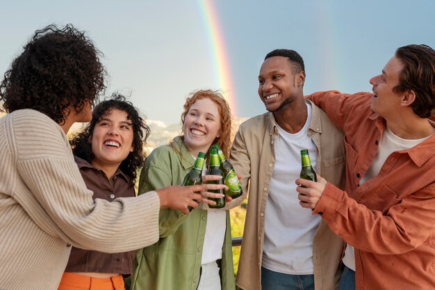 Amigos sonriendo y bebiendo cerveza durante la fiesta al aire libre