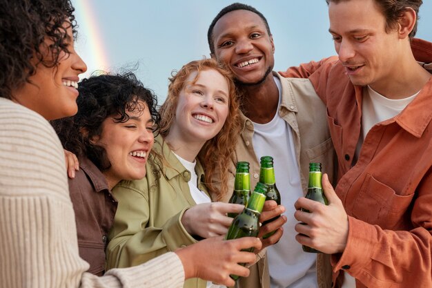 Amigos sonriendo y bebiendo cerveza durante la fiesta al aire libre