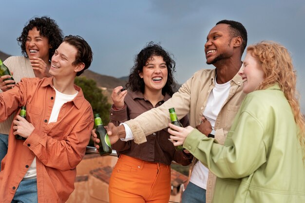 Amigos sonriendo y bebiendo cerveza durante la fiesta al aire libre