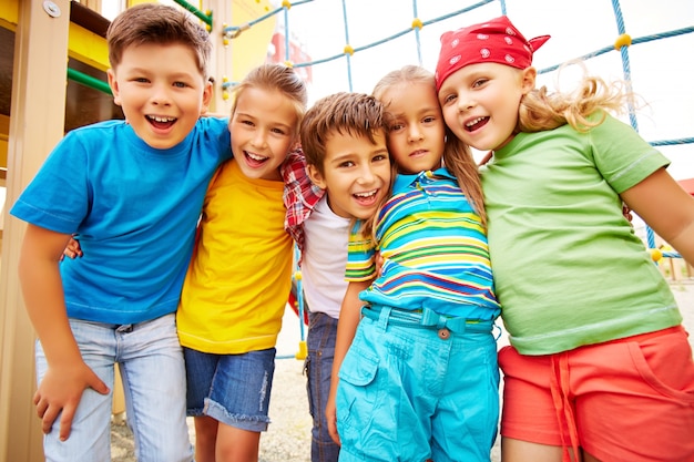 Amigos sonrientes abrazándose en el parque infantil