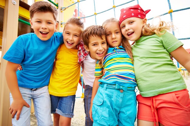 Amigos sonrientes abrazándose en el parque infantil