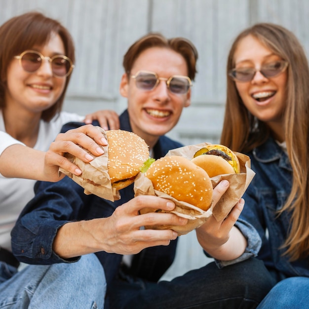 Amigos sonrientes al aire libre disfrutando de hamburguesas