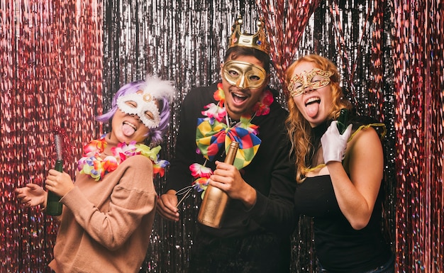 Amigos sonrientes de ángulo bajo con disfraces para fiesta de carnaval