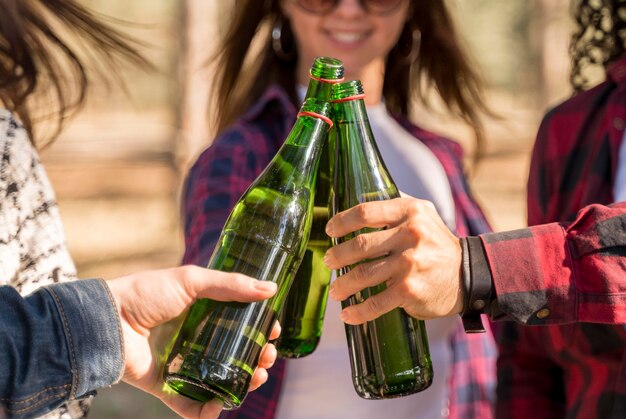 Amigos sonrientes brindando con botellas de cerveza al aire libre