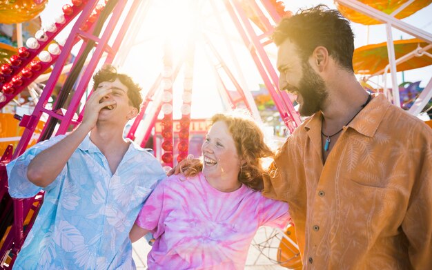 Amigos sonrientes en el parque de atracciones mirando a otro lado