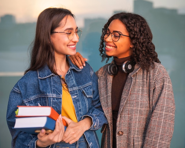 Amigos sonrientes posando junto con libros y auriculares