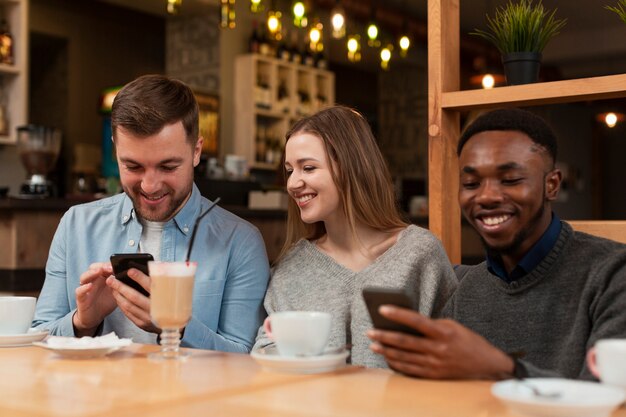 Amigos sonrientes que usan teléfonos en el restaurante