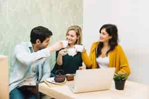 Foto gratuita amigos sonrientes tintineantes tazas de té