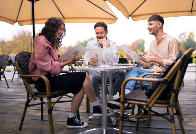 Amigos sonrientes de tiro completo en el restaurante