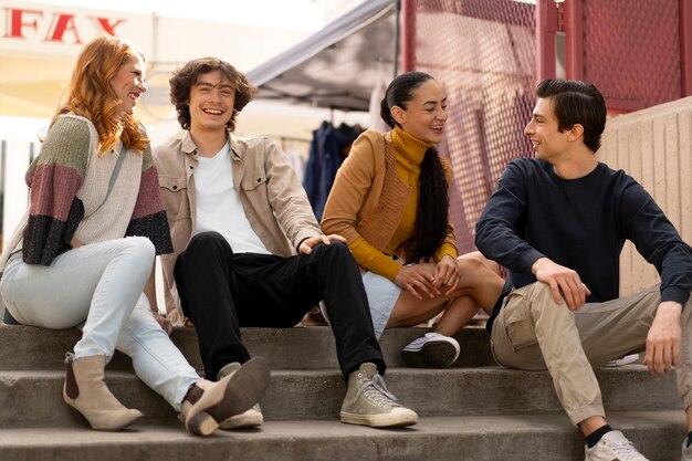 Amigos sonrientes de tiro completo sentados en las escaleras