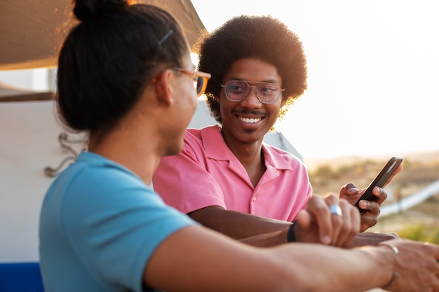 Foto gratuita amigos sonrientes de tiro medio al atardecer