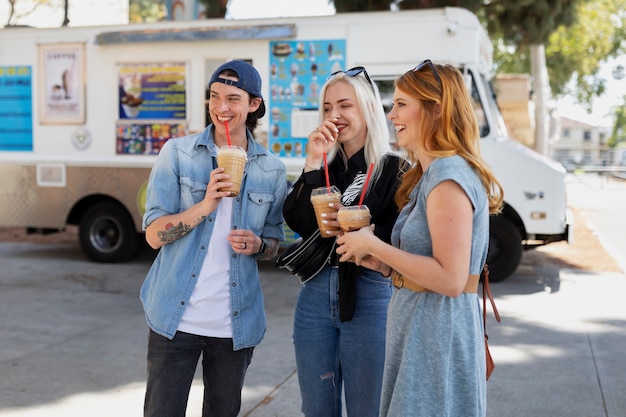 Foto gratuita amigos sonrientes de tiro medio con bebidas