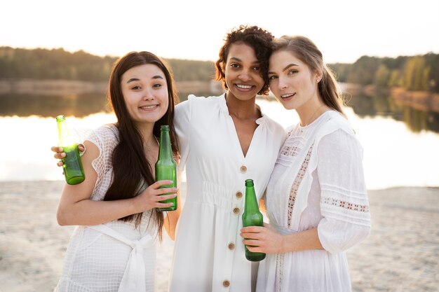 Amigos sonrientes de tiro medio con botellas