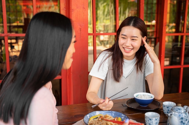 Amigos sonrientes de tiro medio con comida sabrosa