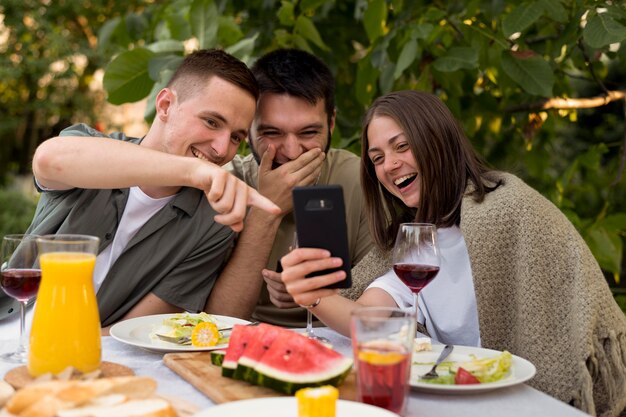 Amigos sonrientes de tiro medio mirando el teléfono