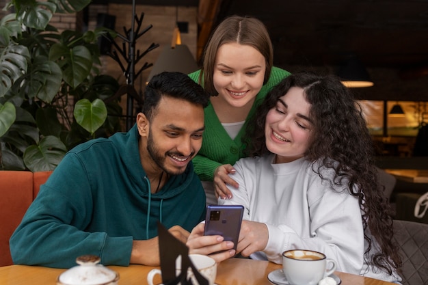 Foto gratuita amigos sonrientes de tiro medio con smartphone