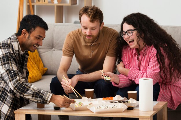 Amigos sonrientes de tiro medio con sushi