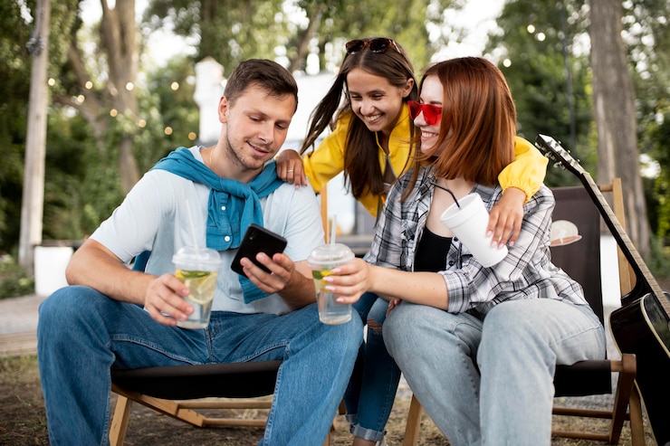 Foto gratuito amigos sonrientes de tiro medio con teléfono