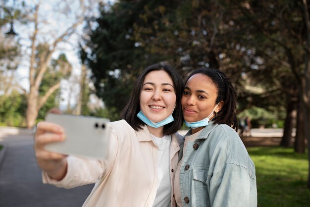 Amigos sonrientes de tiro medio tomando selfie al aire libre