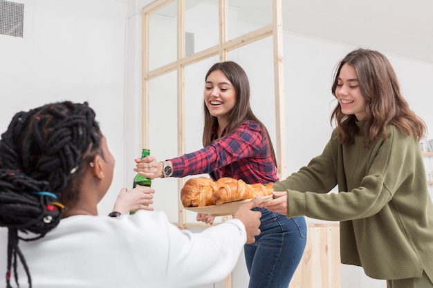 Foto gratuita amigos sonrientes tomando aperitivos en casa