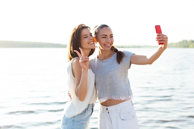Amigos sonrientes tomando un selfie junto a un lago