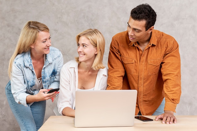 Amigos sonrientes usando una computadora portátil