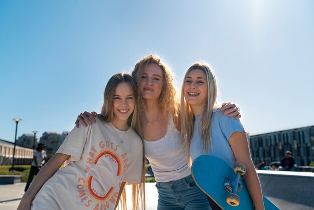 Amigos sonrientes de vista frontal con patineta