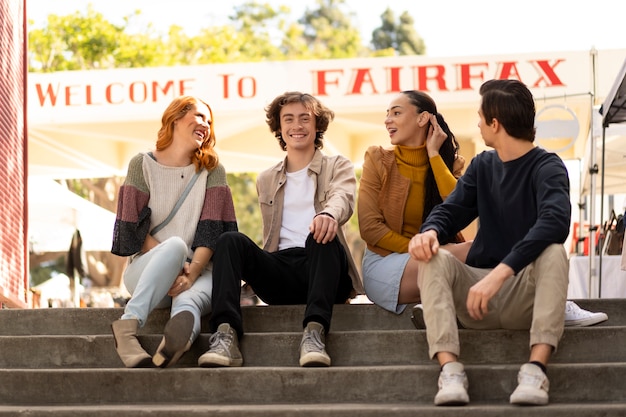 Foto gratuita amigos sonrientes de vista frontal sentados en las escaleras