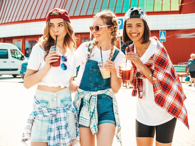 Amigos sosteniendo y bebiendo cóctel fresco licuado beber en vaso de plástico con paja