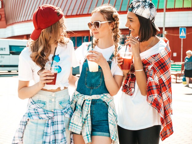 Amigos sosteniendo y bebiendo cóctel fresco licuado beber en vaso de plástico con paja