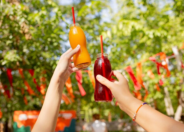 Amigos sosteniendo botellas de jugo fresco en el parque