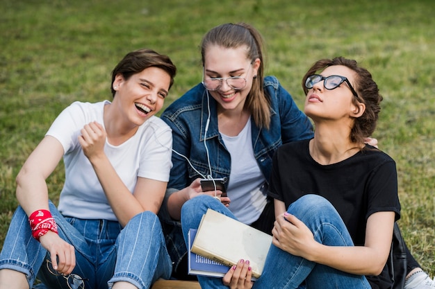 Amigos con teléfono inteligente descansando en el césped del parque