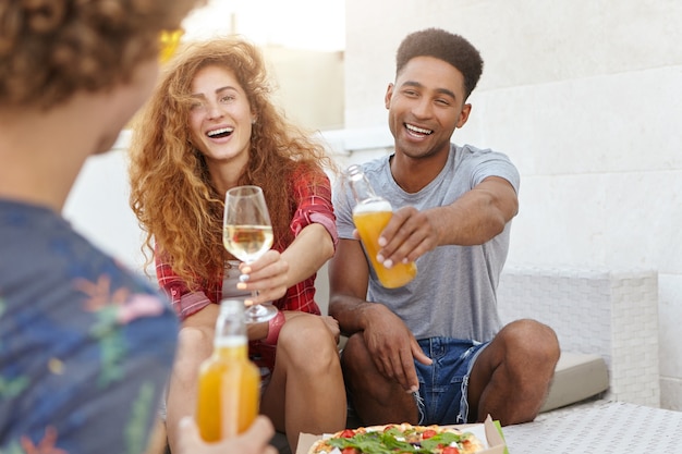 amigos tintinean sus vasos con vino y cerveza