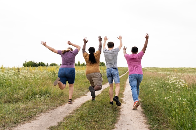 Amigos de tiro completo corriendo al aire libre