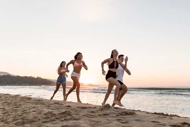 Amigos de tiro completo corriendo en la playa