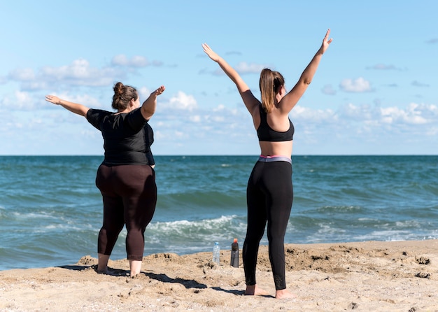 Foto gratuita amigos de tiro completo haciendo deporte en la orilla