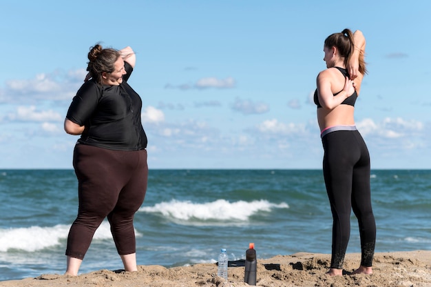 Foto gratuita amigos de tiro completo haciendo deporte en la playa