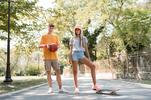 Foto gratuita amigos de tiro completo con patineta y pelota