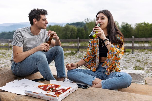 Amigos de tiro completo relajándose con bebidas al aire libre