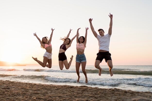 Amigos de tiro completo saltando en la playa