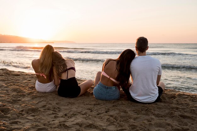 Amigos de tiro completo sentados en la playa