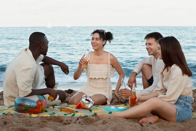 Amigos de tiro completo sentados en la playa